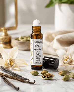 Cardamom Vanilla essential oil bottle with vanilla beans and cardamom pods on a marble surface.